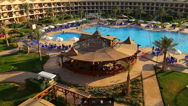 A resort with a central pool, multiple levels of balconies, and outdoor seating areas. - Alhayat Ain El Sokhna (Ataqah)