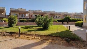 A residential area with multiple two-story houses, a paved walkway, and well-maintained lawns. - Blue Bay Asia Resort El Sokhna (Ataqah)