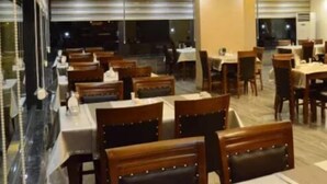 Un restaurante con varias mesas y cabinas, una araña y vistas a la calle.