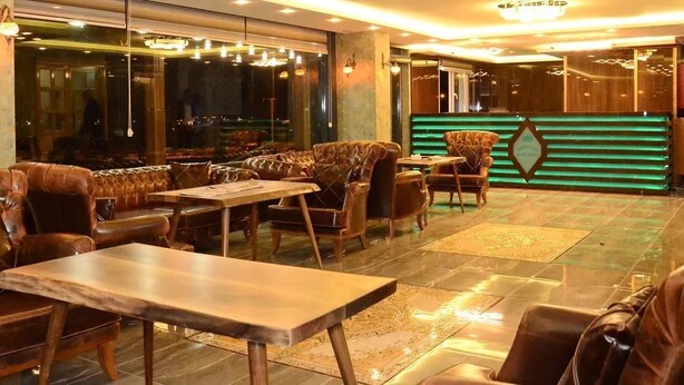 Un restaurante con asientos de cuero, mesas de madera y un letrero de neón verde.