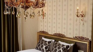Un dormitorio lujoso con una cama grande, techo ornamentado y una araña.