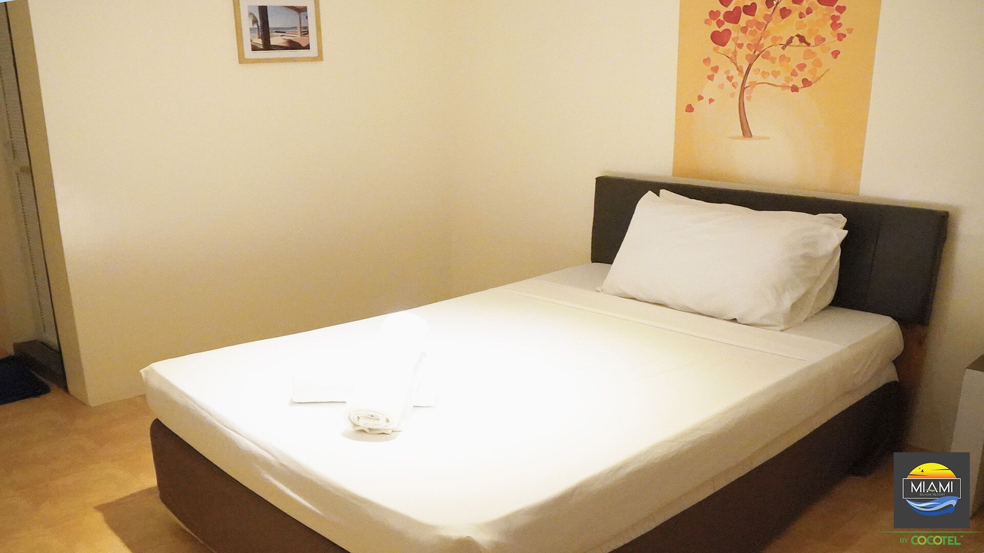 A neatly made bed with white linens in a hotel room.