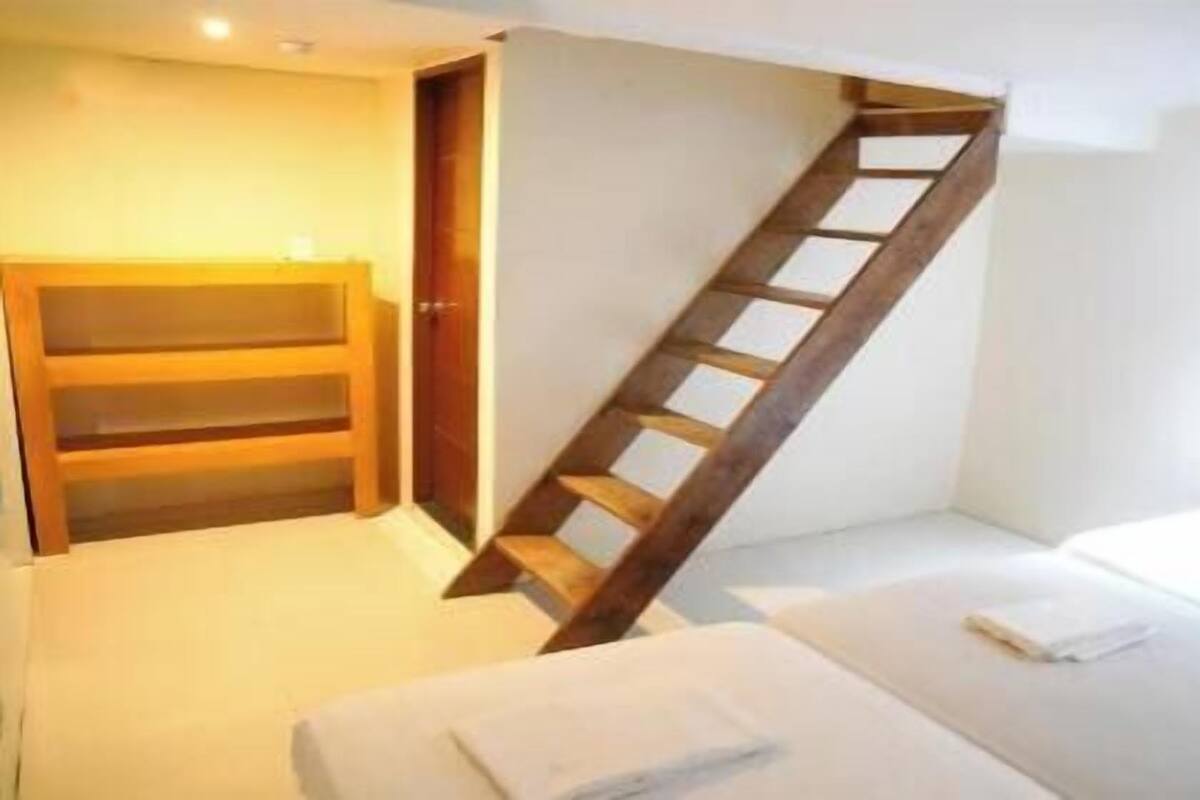 A bedroom with a wooden staircase, a bed, and a wardrobe.