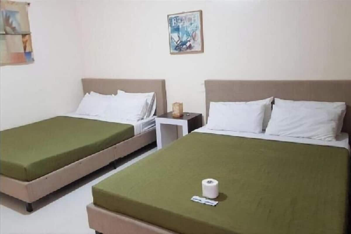 A hotel room with two single beds, a small bedside table, and a wall-mounted picture.