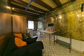 A compact room with a sofa, a television on a stand, a small table, and a cabinet.