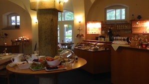 A dining area with a buffet setup, a bar area with glasses, and a large pillar. - Hotel Dein Gutshof (Görlitz)
