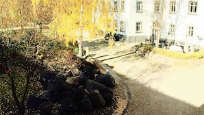 A white building with a tiled roof, a stone pathway, and autumn foliage. - Hotel Dein Gutshof (Görlitz)