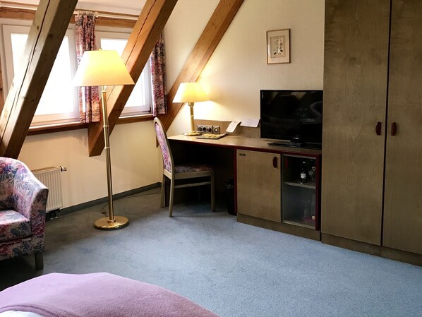 A cozy room with a bed, a desk with a computer, a chair, and a TV. - Hotel Dein Gutshof (Görlitz)