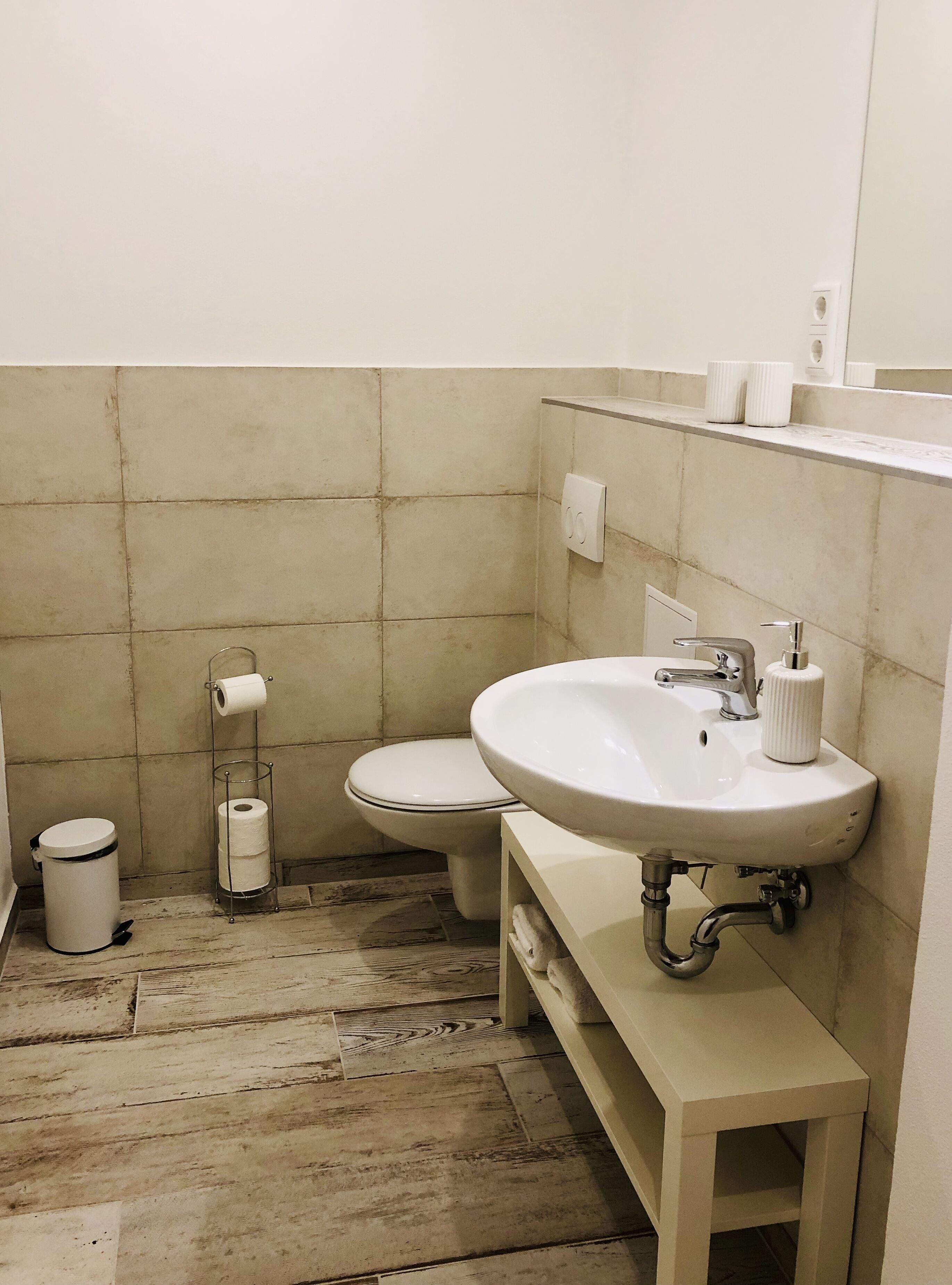 A bathroom with a white sink, toilet, and trash can.