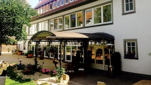 A large building with multiple windows and a covered patio area with outdoor seating. - Hotel Dein Gutshof (Görlitz)