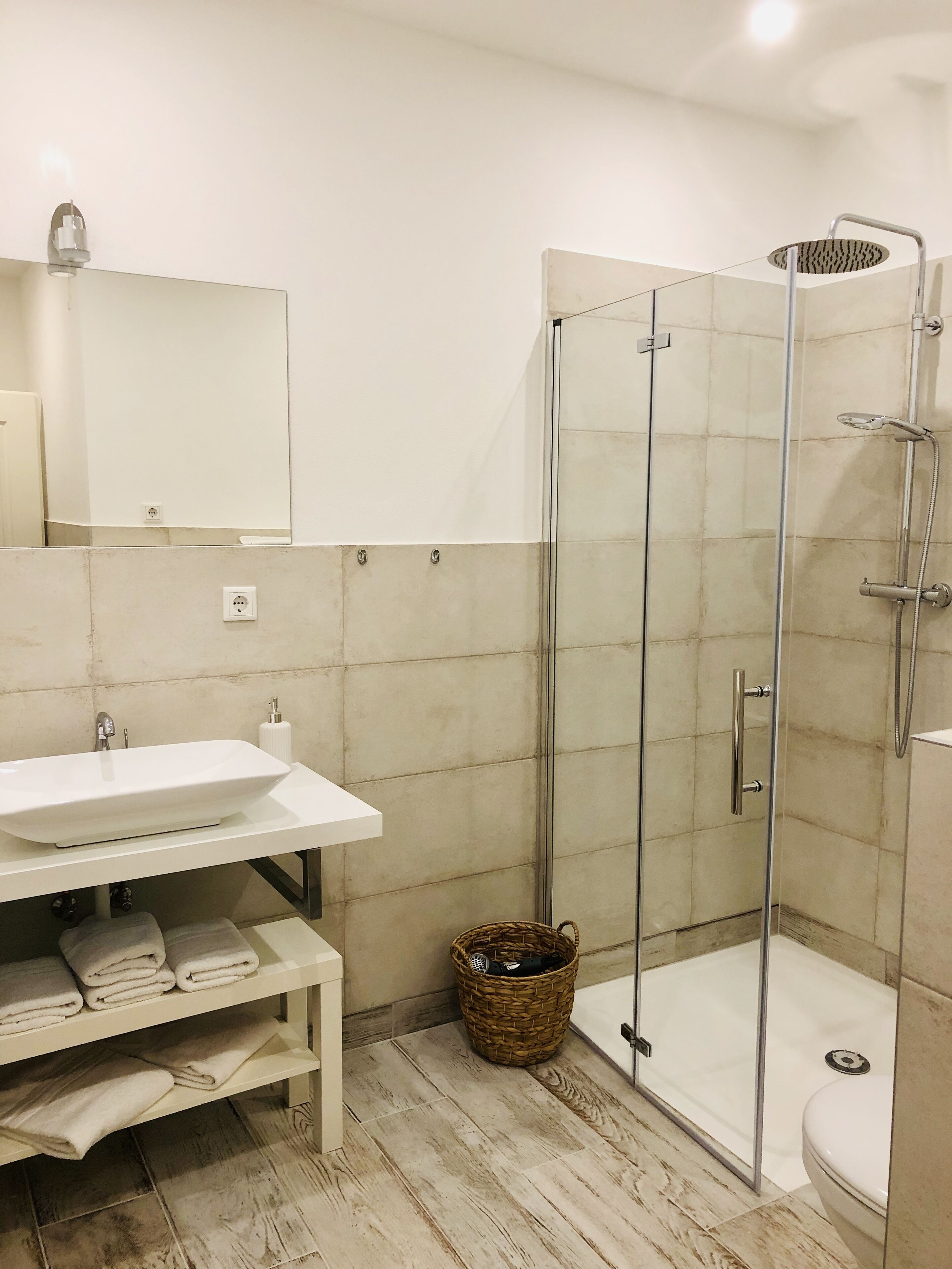 A modern bathroom with a glass-enclosed shower, a white sink, and a mirror above it.