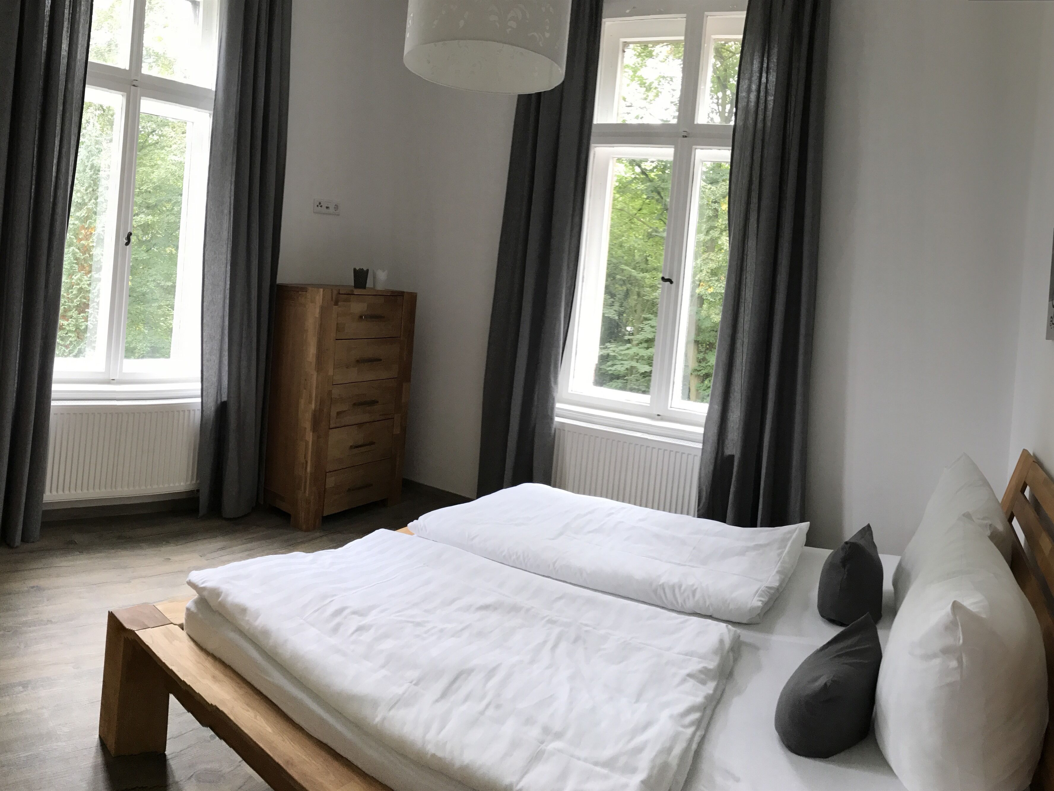 Una camera da letto con un letto, una cassettiera in legno e una finestra con tende.