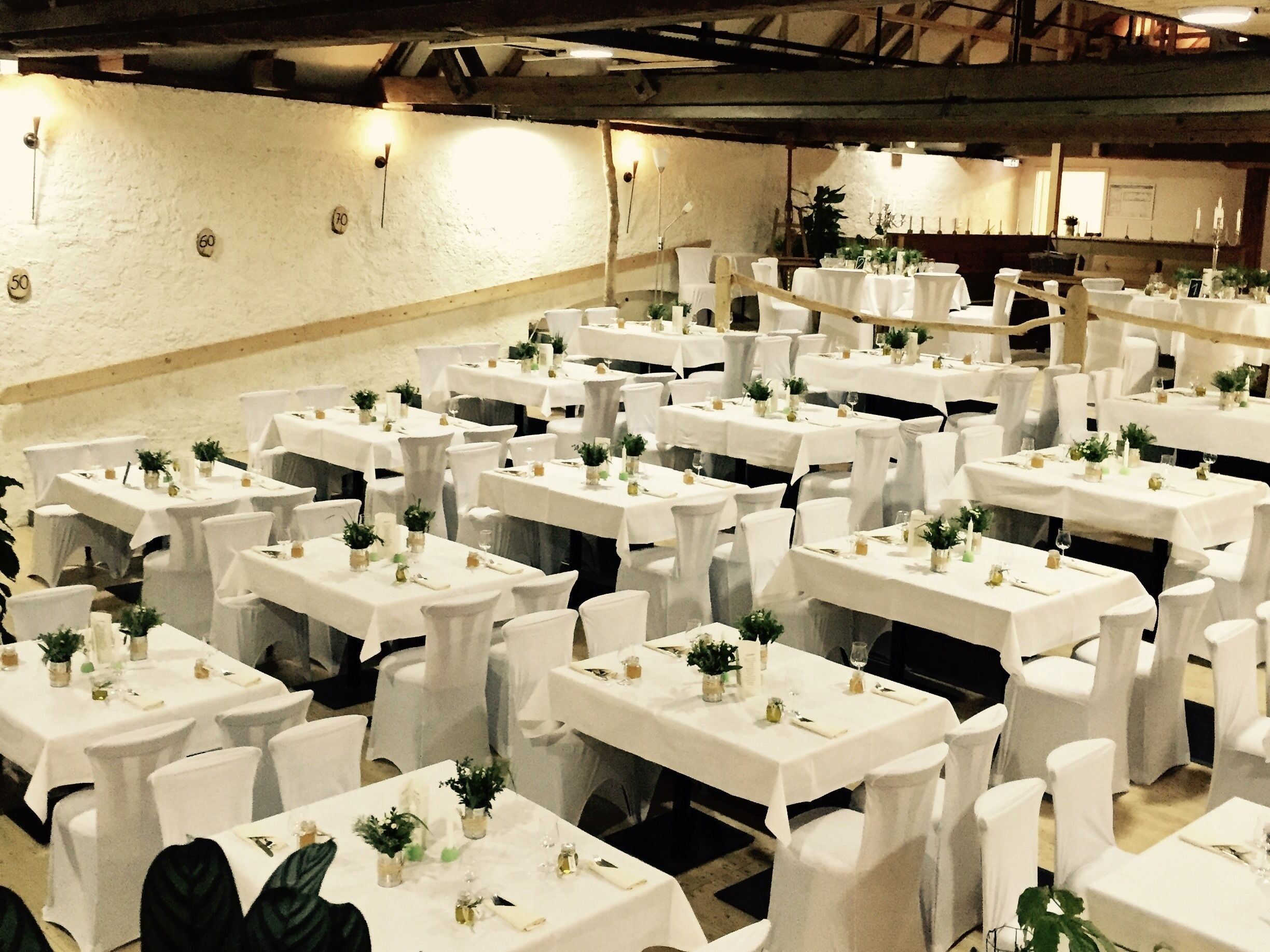 Un salón de banquetes con múltiples mesas dispuestas para comer, cada una con manteles blancos y sillas.