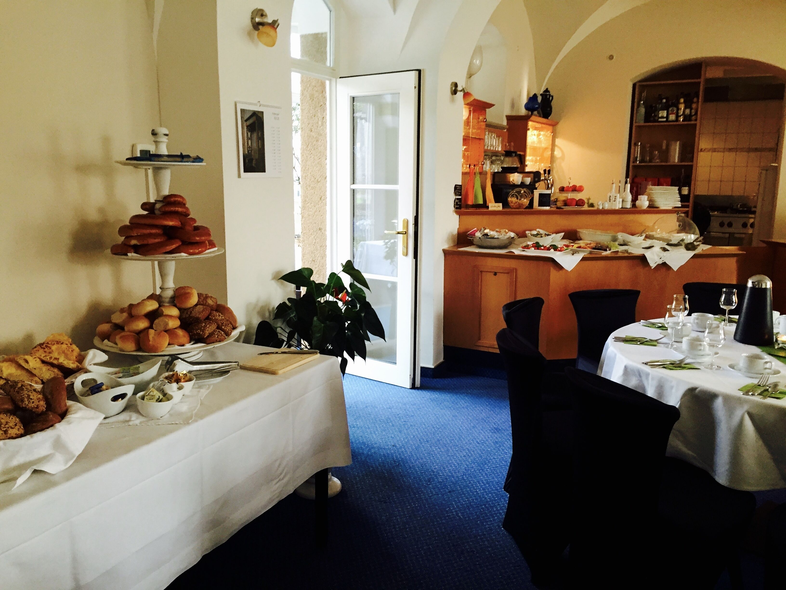Een eetgedeelte met een buffet en een keuken op de achtergrond, plus een eettafel gedekt voor twee personen.