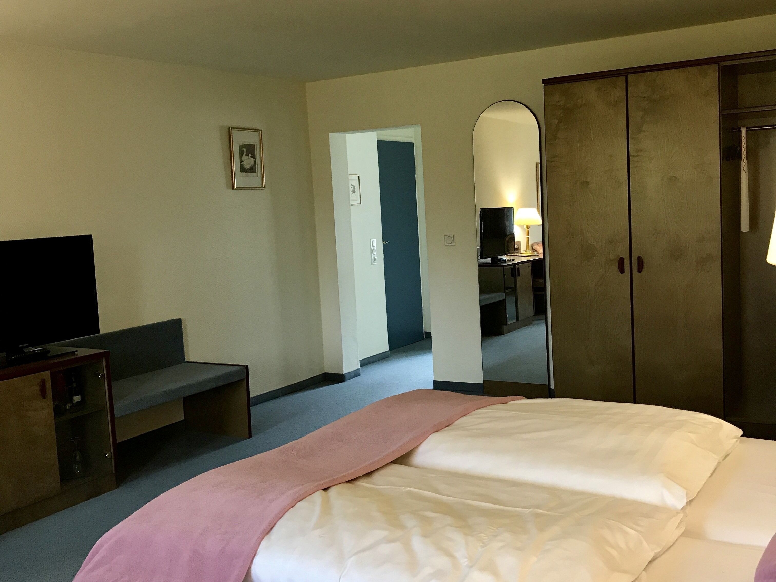 A hotel room with a bed, a television, a desk, and a wardrobe.