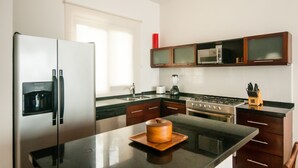 A modern kitchen with a stainless steel refrigerator, a built-in microwave, a stove, and a coffee maker.