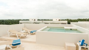 A rooftop pool area with lounge chairs and a hot tub.