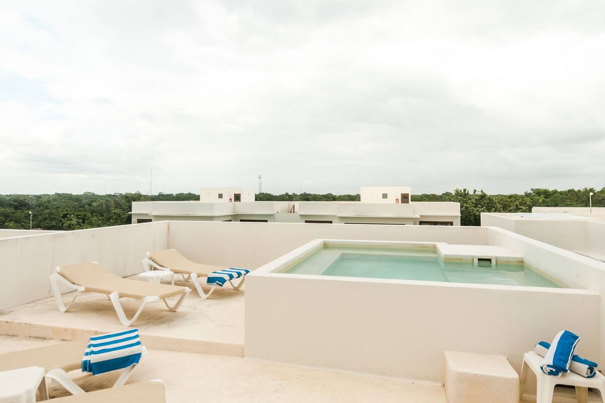 Un espace piscine aménagé sur le toit, avec des chaises longues et un jacuzzi.