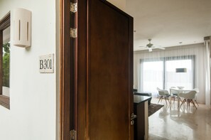 Une pièce avec une porte en bois, une pancarte indiquant « B301 », un coin repas avec une table et des chaises, et un ventilateur de plafond.