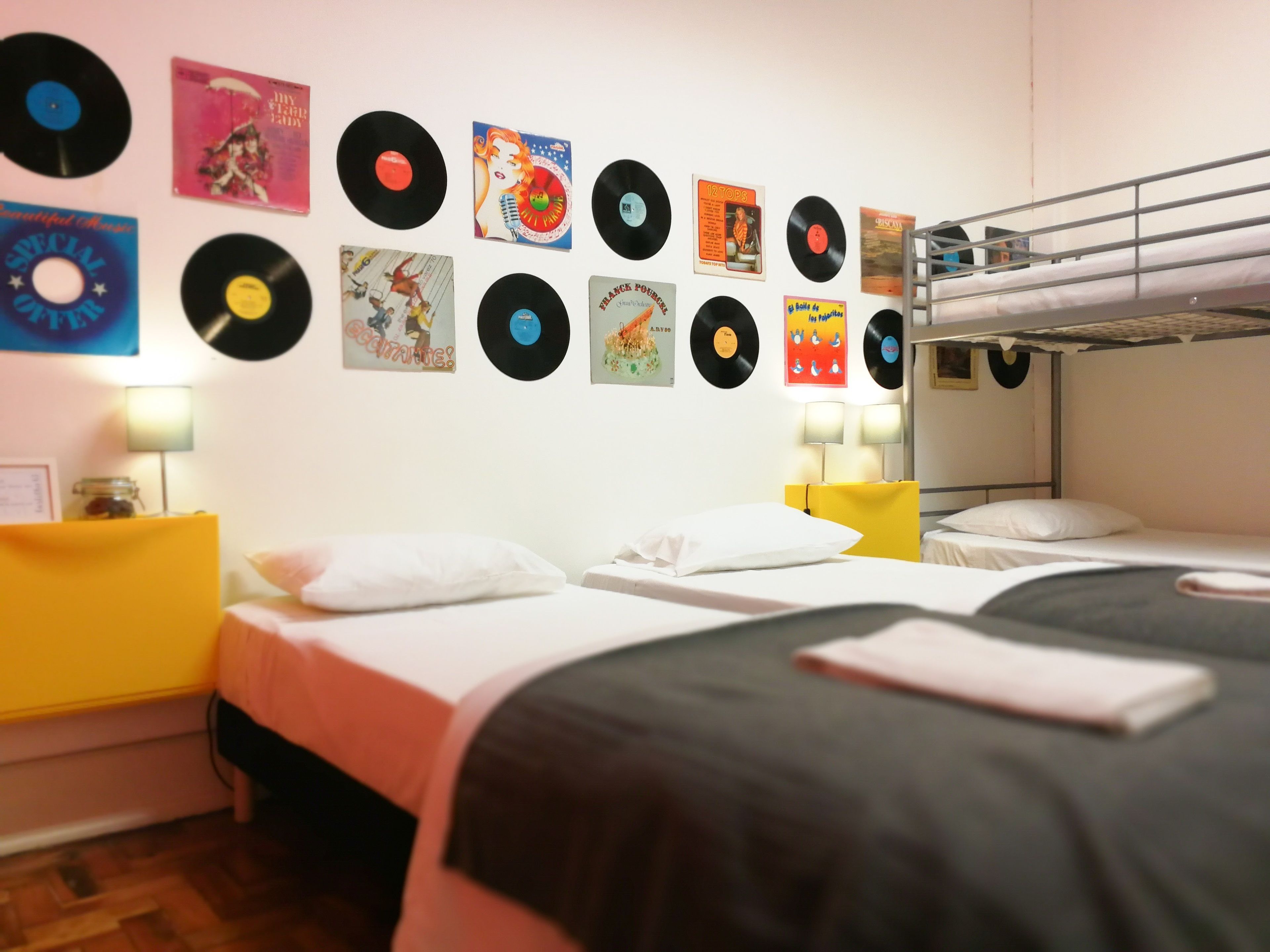 Habitació amb literes, una paret decorada amb discos de vinil i làmpades de nit.