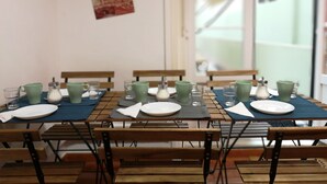 Un comedor con mesas y bancos de madera, cada conjunto con platos, vasos y tazas verdes.