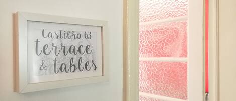A framed sign with the text "casillho 63 terrace & tables" on a white wall.