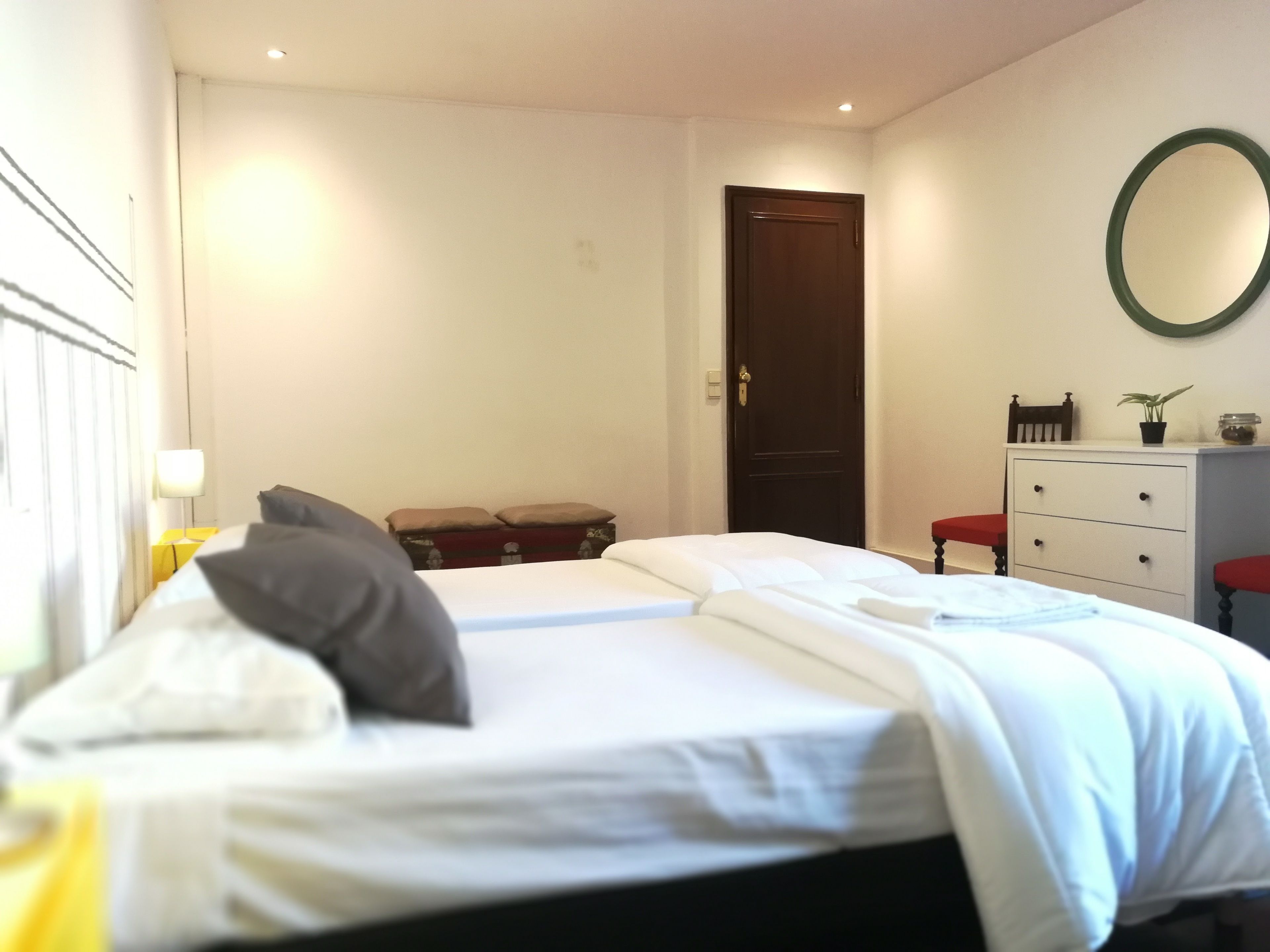 A hotel room with a bed, a dresser, a mirror, and a door.