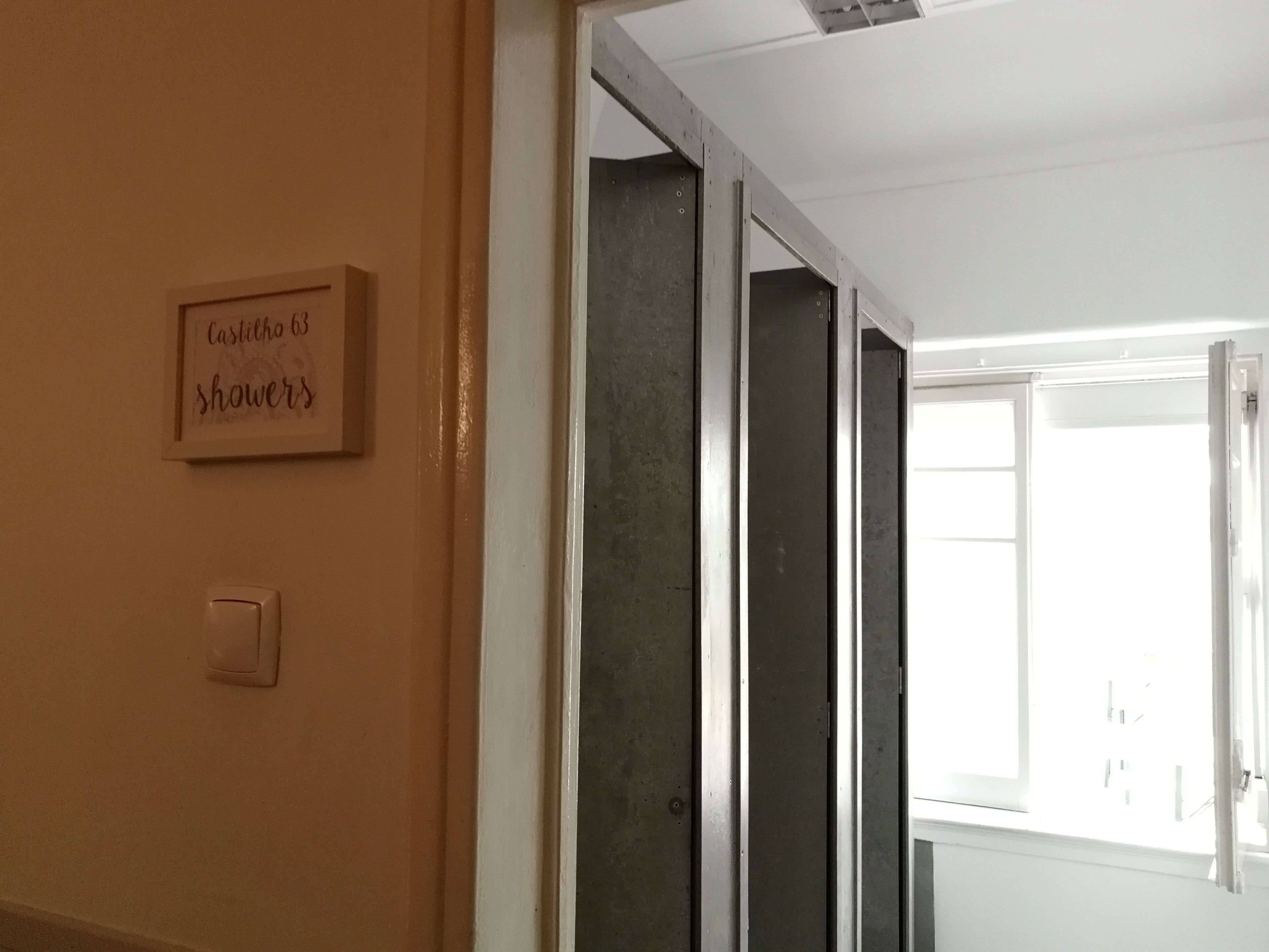Un couloir avec une pancarte indiquant « 65 douches Castilho » et une porte donnant sur une pièce.