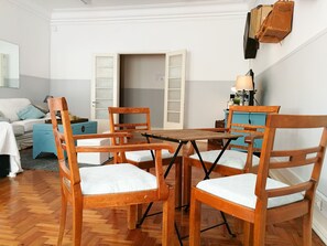 Une pièce comprenant une table à manger en bois, entourée de quatre chaises, d’un canapé et d’une armoire bleue.