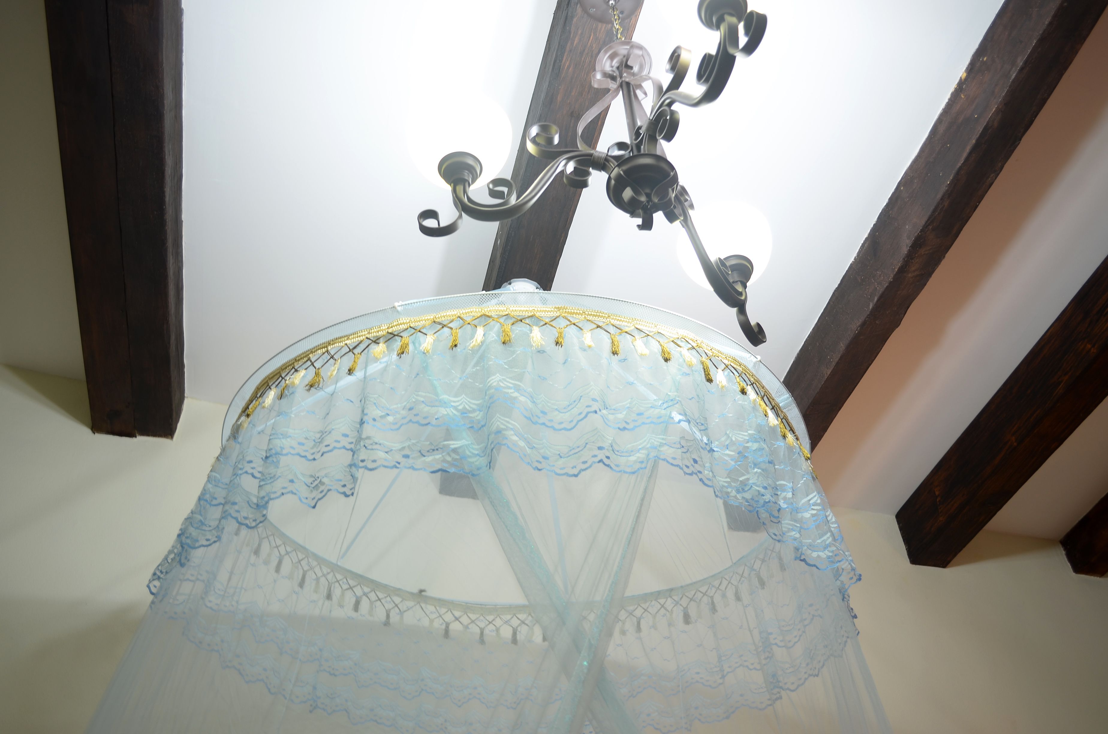 A chandelier with a blue, sheer, ruffled canopy.