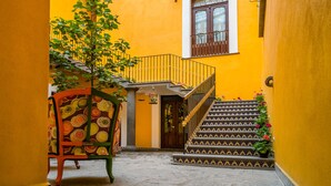 Une ruelle étroite avec un escalier menant à un balcon, une chaise et une porte.