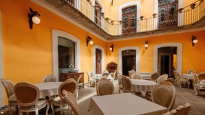 Un espace repas comprenant plusieurs tables et chaises, un balcon avec une balustrade et un escalier menant à un niveau supérieur.