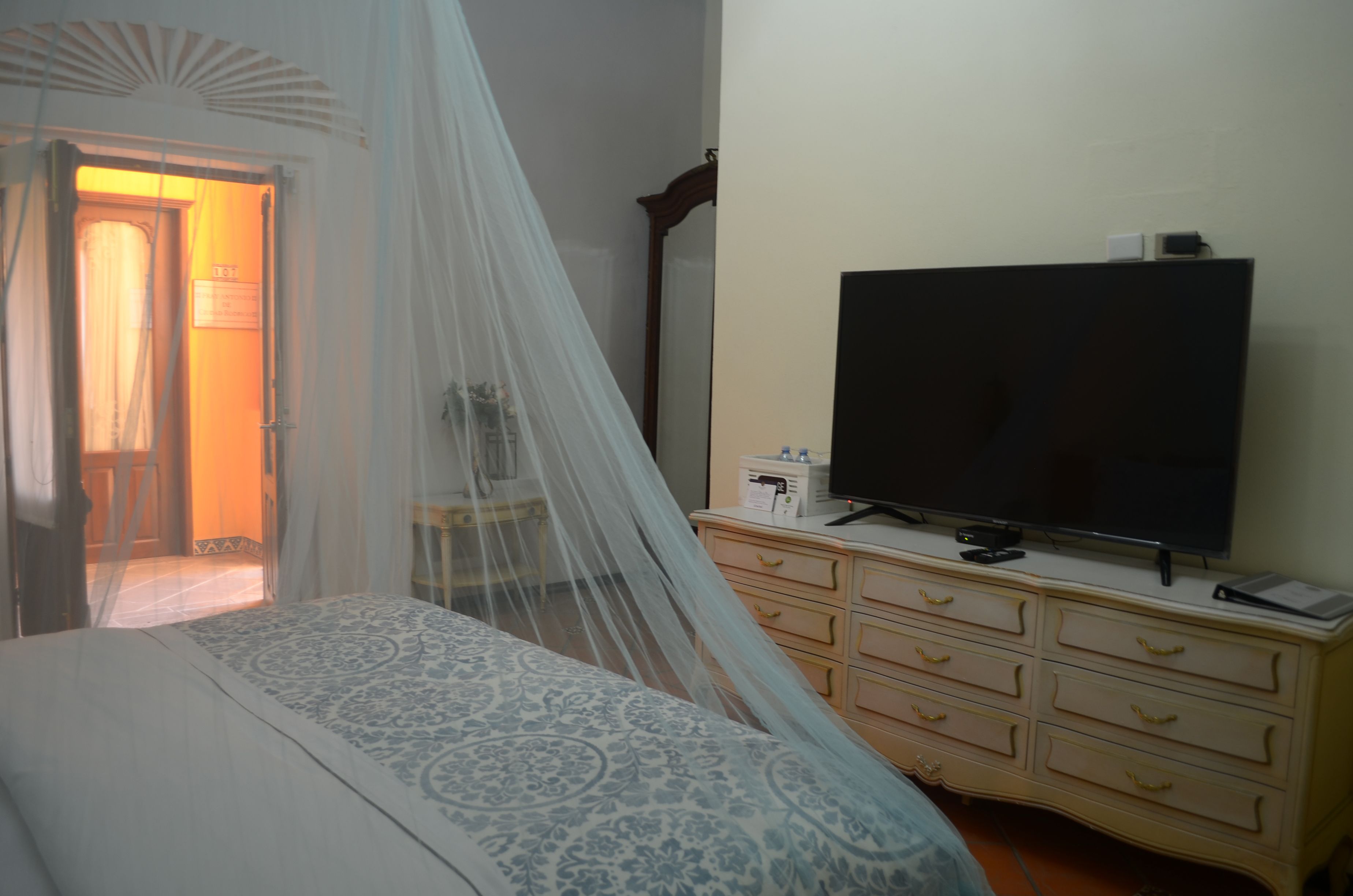 A bedroom with a bed, a television on a dresser, and a mirror.