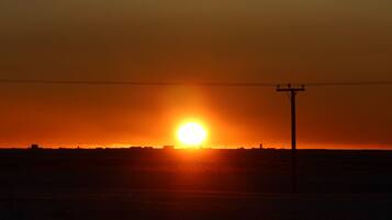 Atardecer sobre una llanura extensa con un poste de electricidad al frente.