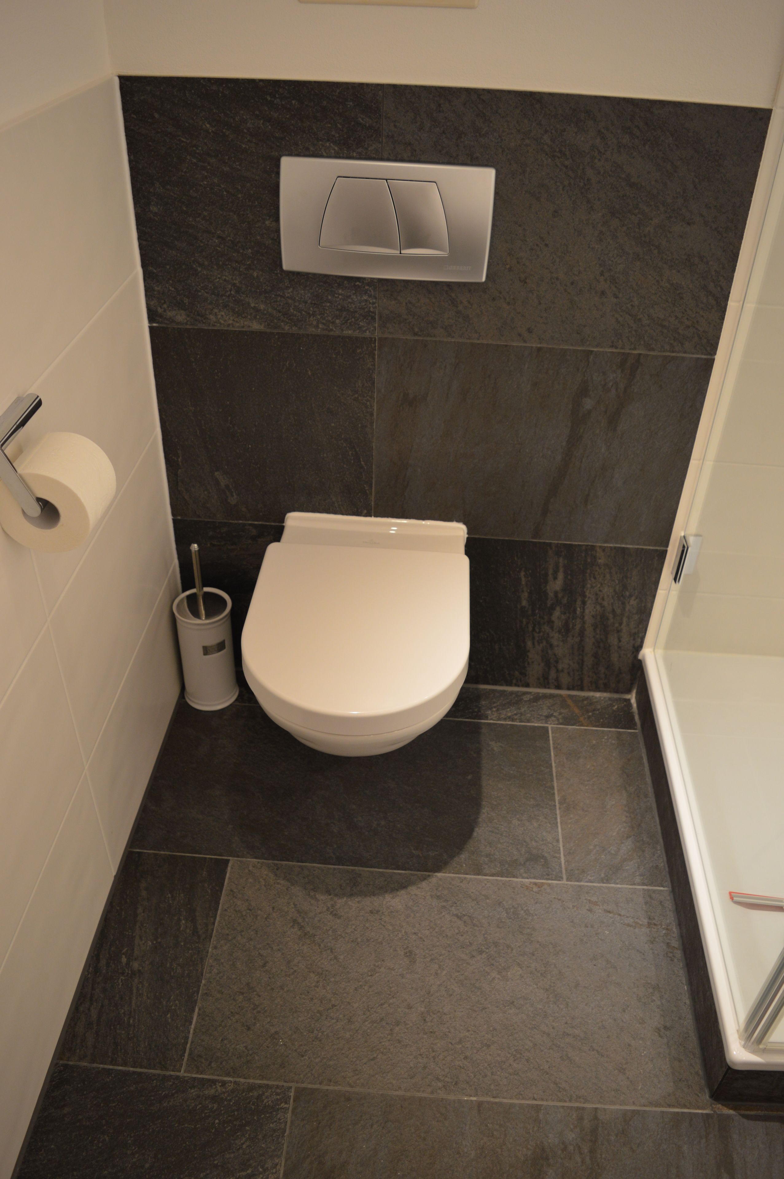 Ein Badezimmer mit Toilette, Papierhalter und Mülleimer.
