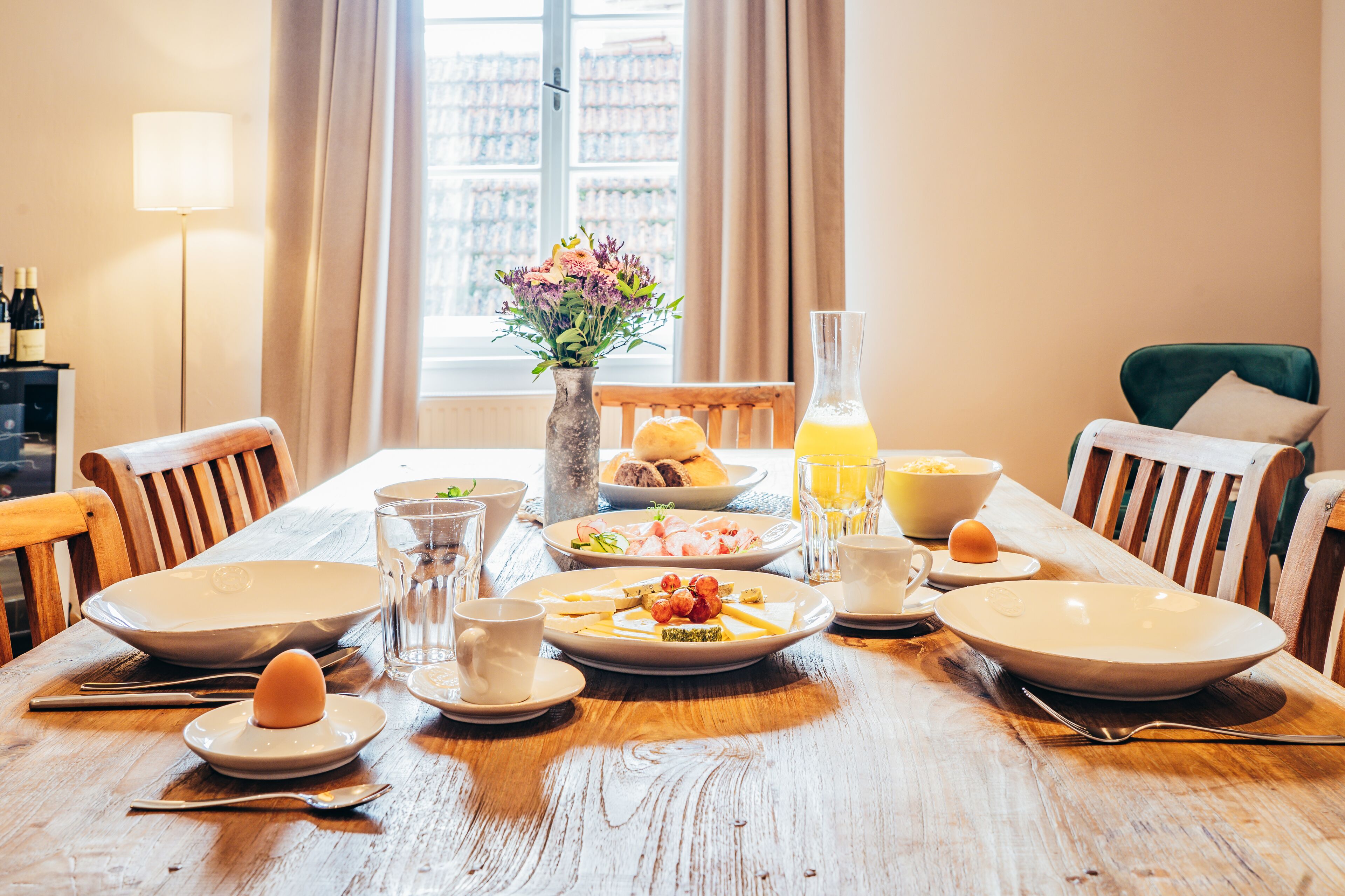 A dining table set with plates, glasses, and a vase of flowers.