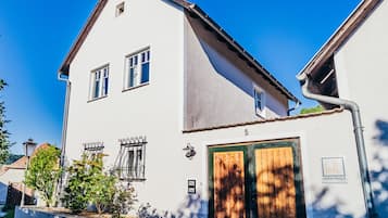 A two-story building with a white facade, a wooden door, and a small window.
