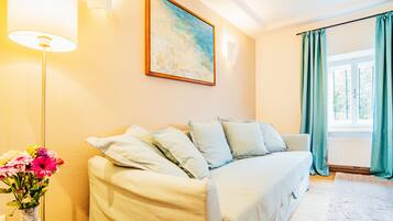 Una habitación acogedora con un sofá, un jarrón de flores y un cuadro en la pared.