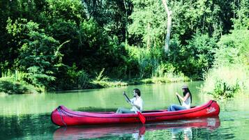 A red canoe on a calm river surrounded by dense greenery.
