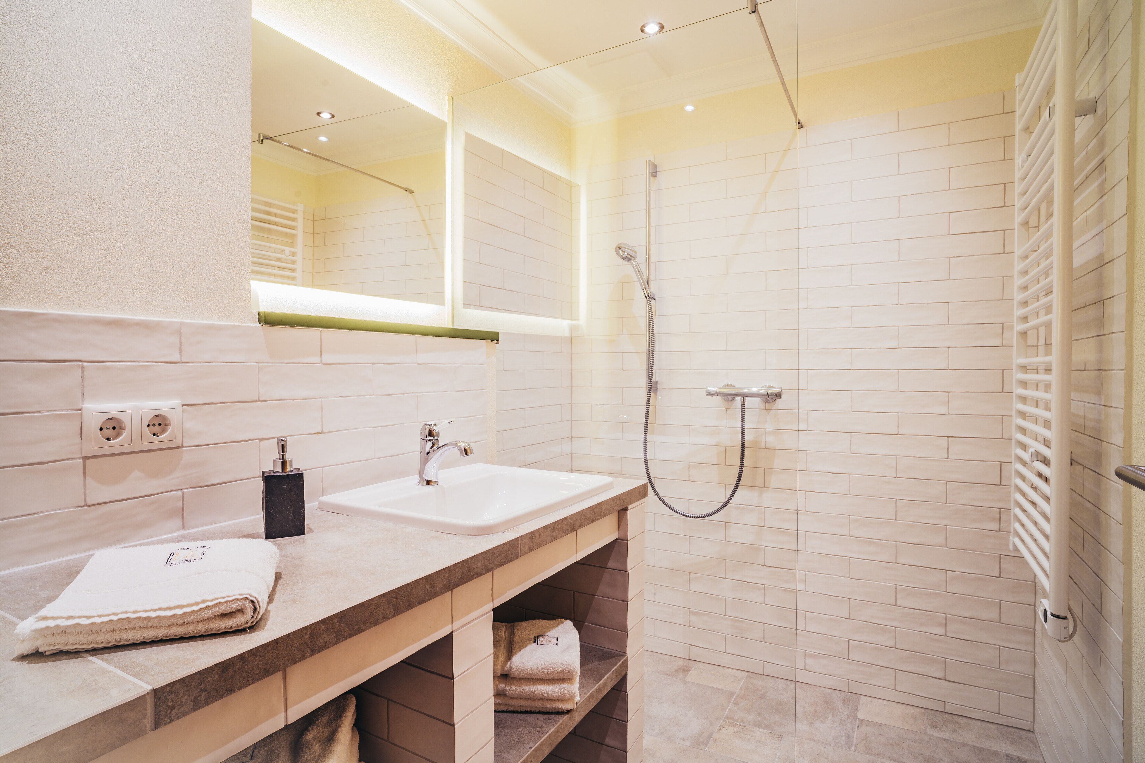 A modern bathroom with a sink, mirror, and shower.