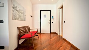 Un corridoio con una panca di legno, una porta con un cartello e un telefono fissato al muro.