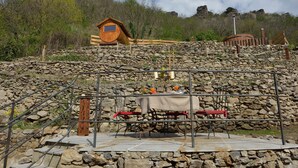 A rustic outdoor dining area with a stone wall backdrop, a wooden structure, and a metal railing. - Heritage Dürnstein (Durnstein)