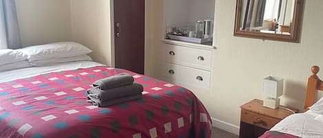 A hotel room with two beds, a dresser, a mirror, and a ceiling fan.