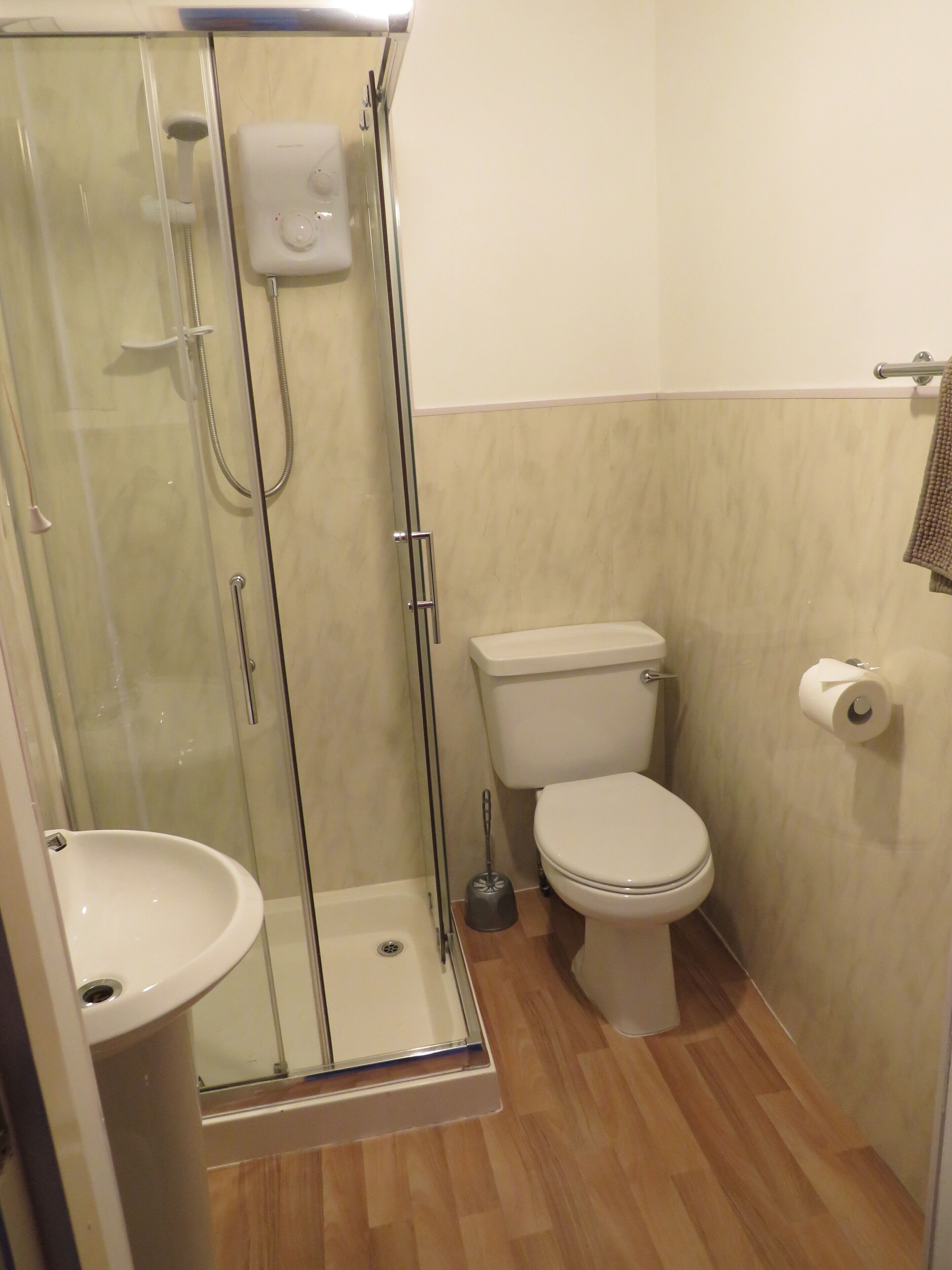 Ein Badezimmer mit Duschkabine, Toilette, Waschbecken und Handtuchhalter.