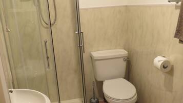 Ein Badezimmer mit Duschkabine, Toilette, Waschbecken und Handtuchhalter.