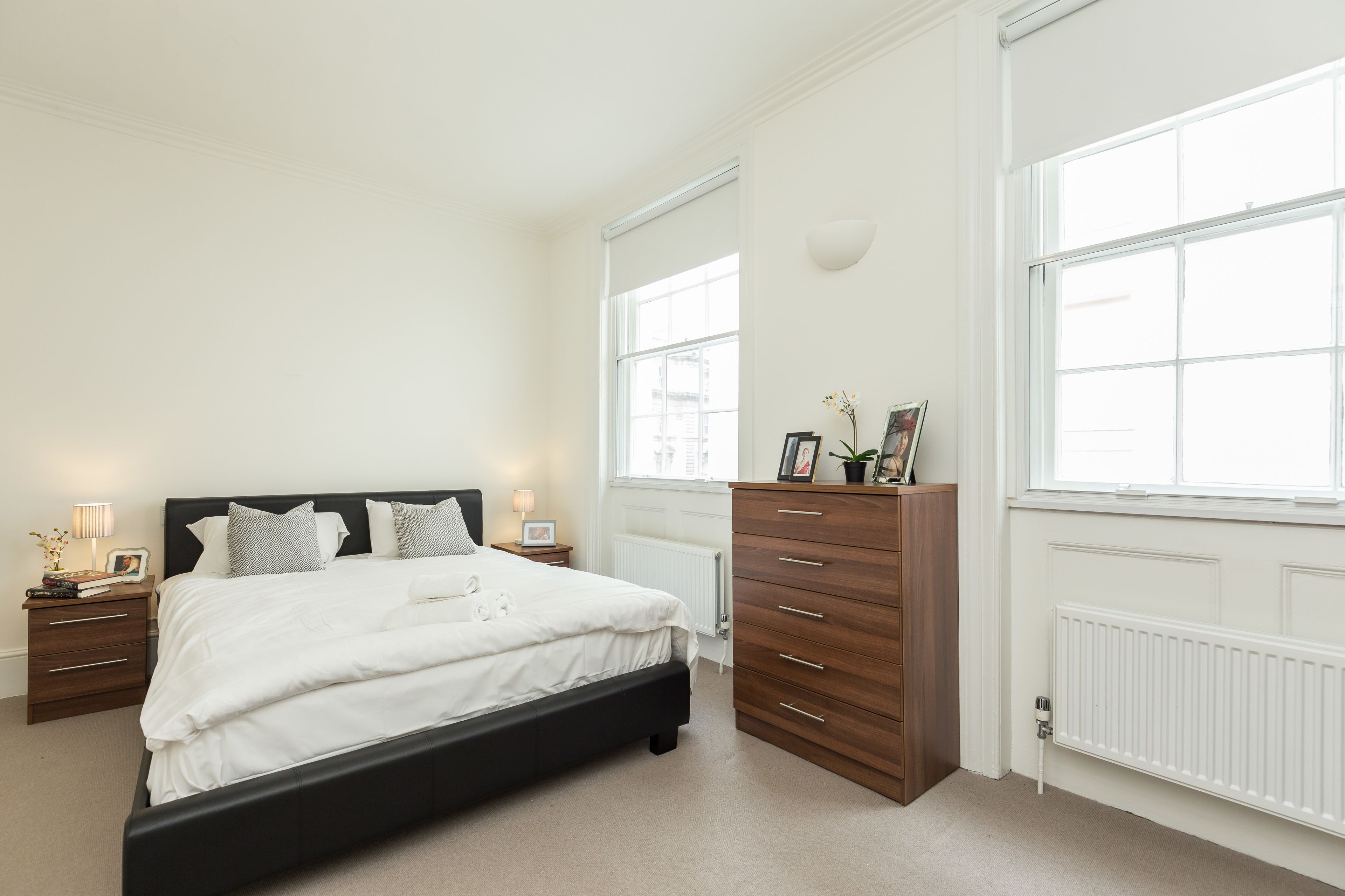 A bedroom with a large bed, a dresser, and two bedside tables with lamps.