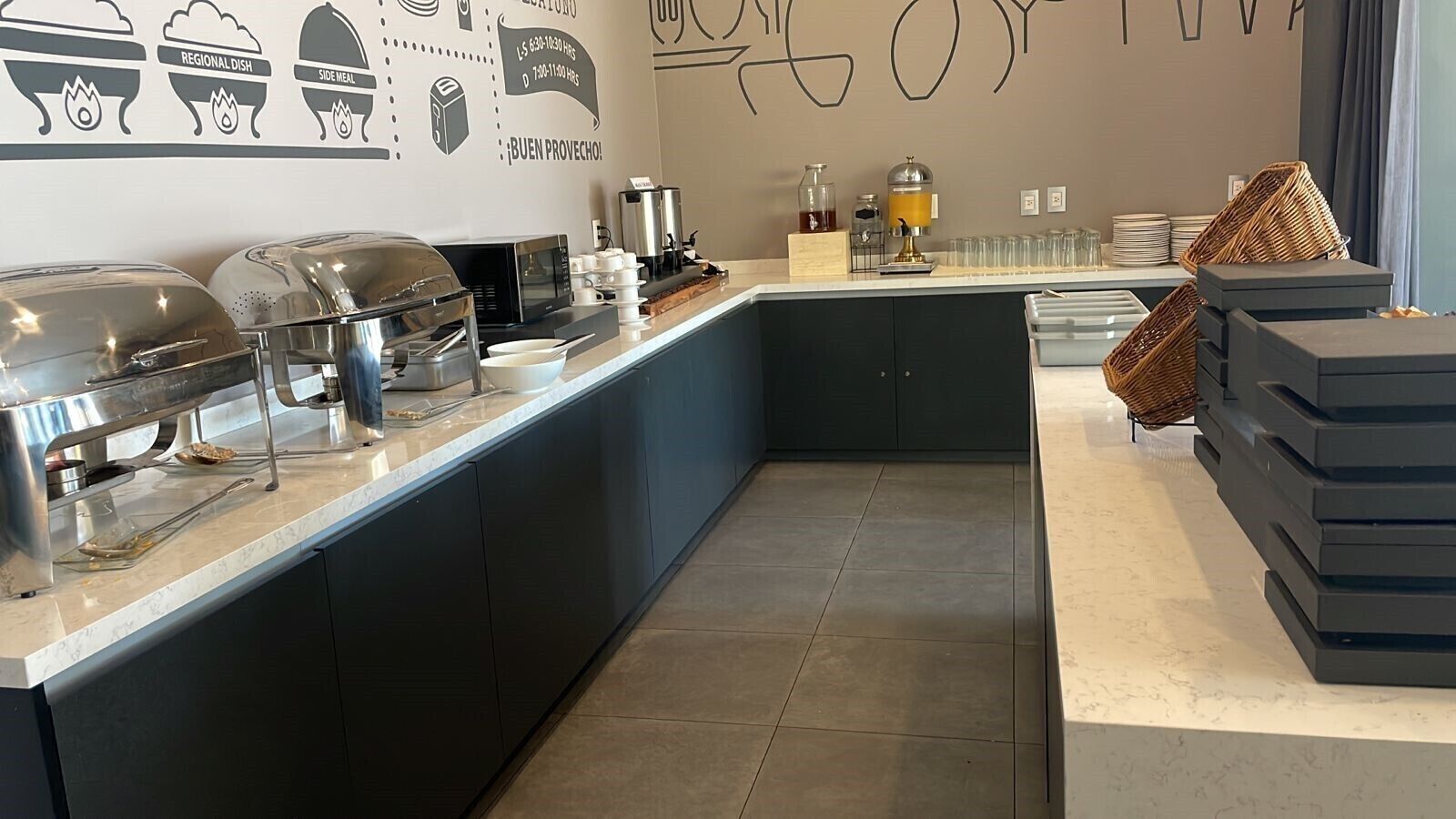 A modern kitchen with a buffet setup, including a grill, microwave, and various food containers.