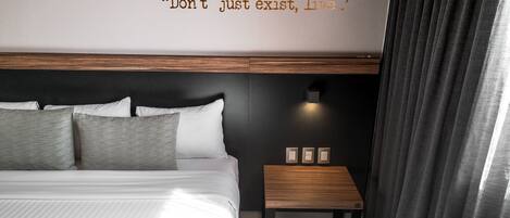 Una habitación de hotel moderna con una cama grande, una mesita de noche y una lámpara de pared.