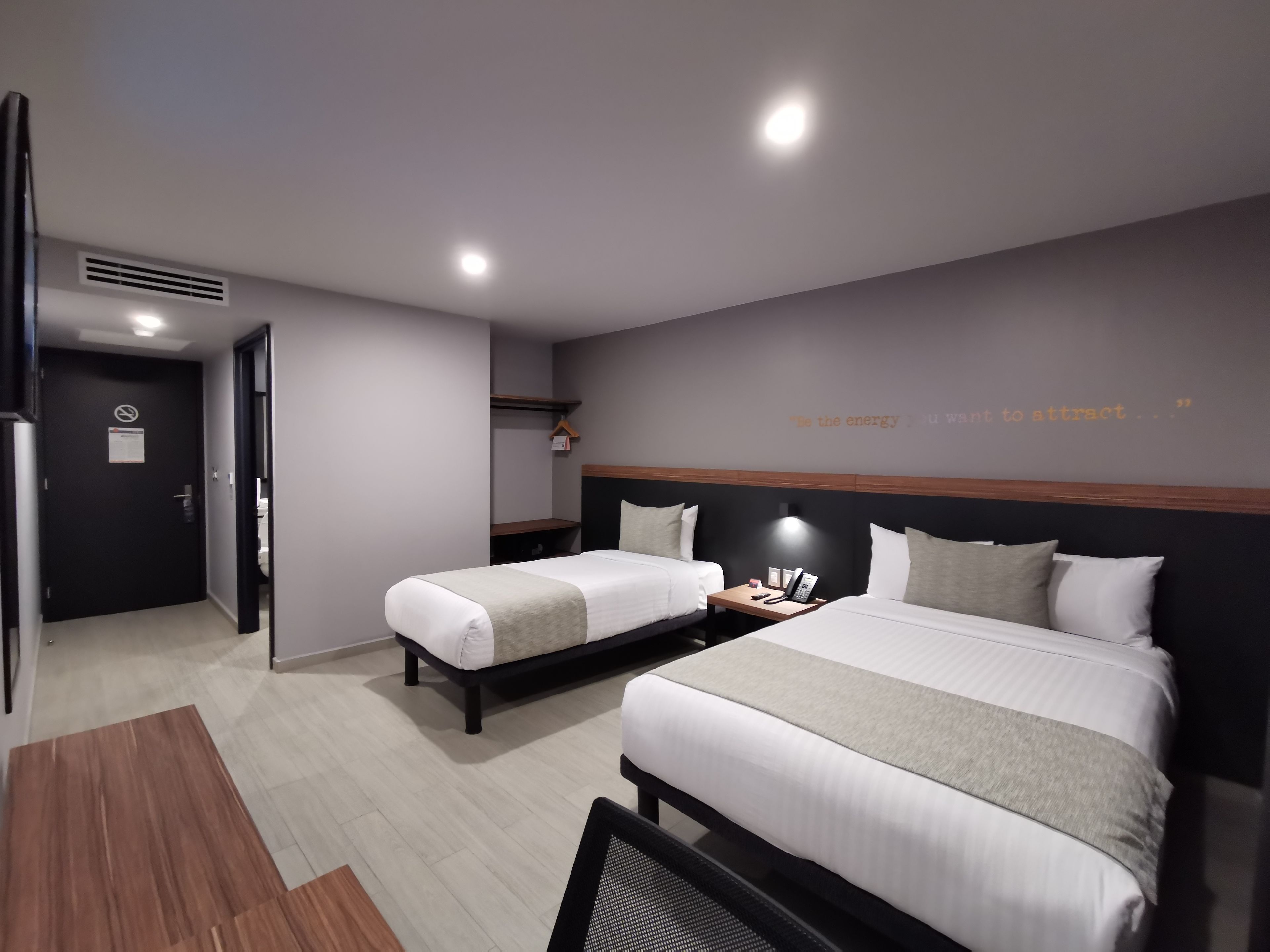 Una habitación de hotel moderna con dos camas, un escritorio y una estantería en la pared.