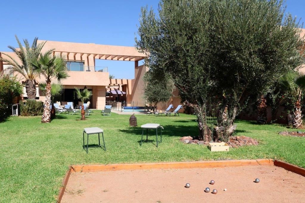 A courtyard with a pool, lounge chairs, and a bocce court.